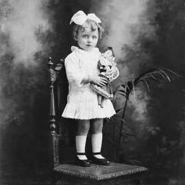 Studio portrait of a young girl standing on a chair.  Family name Charlesworth.