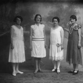 A group of four unidentified women in front of a painted studio background.