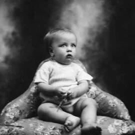 Studio portrait of a seated baby.  Family name possibly Garney.