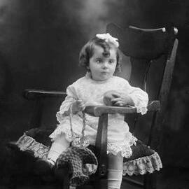 Studio portrait of a young girl seated in a carver chair.  Family name Cresswell.