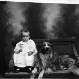 Studio portrait of a baby and a collie dog.   Family name Dempsey.