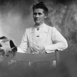 Studio portrait of a woman wearing a brooch containing the portrait of a man.