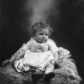 Studio portrait of a baby wearing a dress.  Family name Parker.