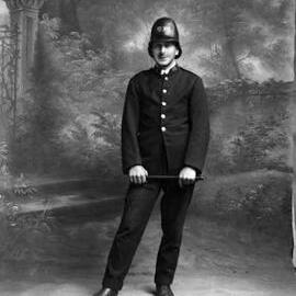 Studio portrait of a young man dressed in a police uniform. Family name Trembath.