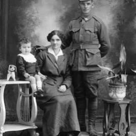 Studio portrait of a woman, a baby and a man wearing an Australian Army uniform.