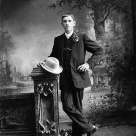 Studio portrait of a well dressed young man holding a hat.  Family name Blackney.