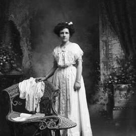 Studio full-length portrait of a young woman in a full length dress.  Family name Dudley.