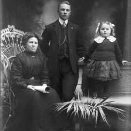 Studio portrait of a woman, a young man and a young girl.  Family name White.