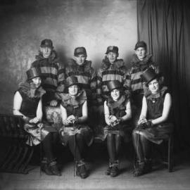 A posed group of four women and four men in matching theatrical costume.