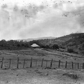 A rural scene showing farmland, a  brick house and a timber cottage, possibly in north-eastern Victoria.