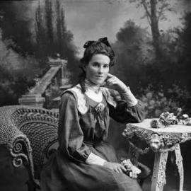 Studio portrait of a young woman holding a rose.  Family name Mills.