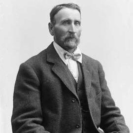 Studio portrait of a man with a beard and wearing a bow tie.