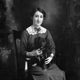 Studio portrait of  a seated woman holding a dog.  Family name Johnstone