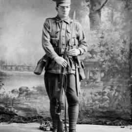 Studio portrait of a man in an Australian Army uniform holding a rifle.  Family name ‘Wright.
