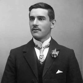 A half-length indoor portrait of Mr. C. Williams wearing a paisley tie.