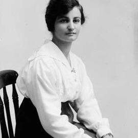 Portrait of a seated young woman wearing a white blouse.