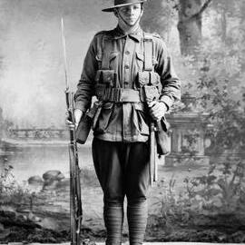 Studio portrait of a man in an Australian Army uniform holding a rifle.  Family name ‘Wright.