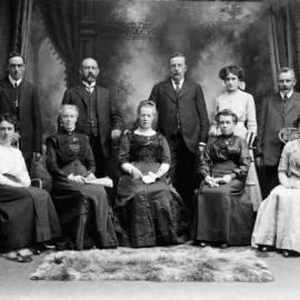 An unidentified posed group of ten adults in a photograhic studio.