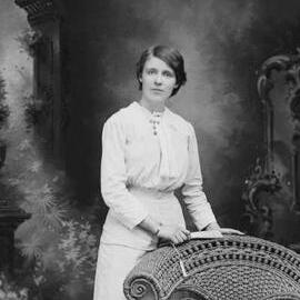 Studio portrait of  a young woman holding a fan.  Possibly Miss Boives.