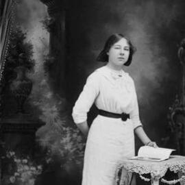 Studio portrait of a young woman wearing a white dress.   Family name Cameron.