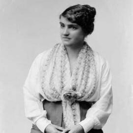 Portrait of a seated woman wearing a large scarf.
