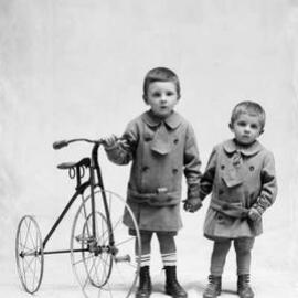 Studio portrait of two boys and a tricycle.  Family name Cronin.
