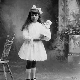 Studio portrait of a girl holding a doll.   Family name Page.