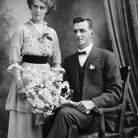 Studio portrait of a woman standing alongside a seated man.  Family name Foster.