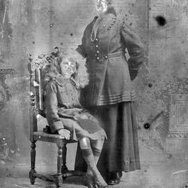 Studio portrait of a standing woman with a seated girl -  family name Moore.