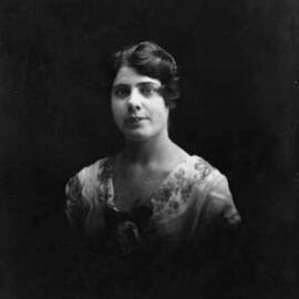 Studio portrait of a young woman wearing a rose.  Family name possibly Neilson.