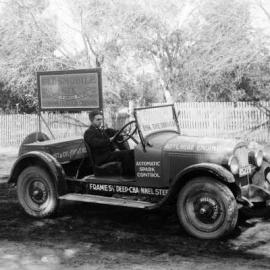 A man sitting at the wheel of an Oldsmobile demonstration car.