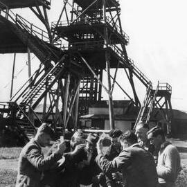 Miners playing cards in front of a poppet head at Wonthaggi, State Coal Mine, Victoria in 1949.