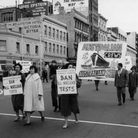 Protesters marching and carrying banners in Flinders Street, Melbourne.