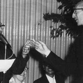 The Rev Frank Hartley handing money to Sam Goldbloom at an unknown event in Melbourne.