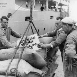 Waterside workers on the Melbourne waterfront holdng a sign supporting Australian seamen.