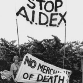 Joan Coxsedge holding "Stop AIDEX" banner at the Australian International Defence and Equipment Exhibition (AIDEX) protest, Canberra, 26 November 1991.