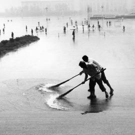 Men sweeping rainwater in Tiananmen Square, Beijing, China.