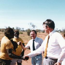 Malcolm Fraser greeting an Aboriginal Australian man at a settlement in the Northern Territory.