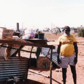 An Aboriginal Australian man standing alongside a dwelling in the Northern Territory.
