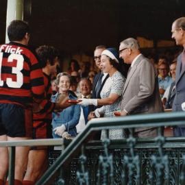 Queen Elizabeth II exchanging a gift with an unidentified rugby player in Sydney during her 1977 official Australian visit.