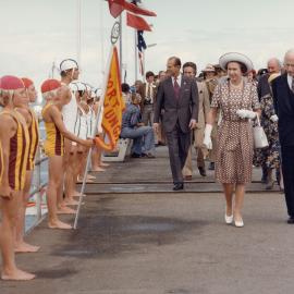 Queen Elizabeth II and the Lieutenant-Governor of South Australia walking past a group of junior lifesavers on Glenelg Jetty, South Australia, during the Queen's 1977 official Australian visit.
