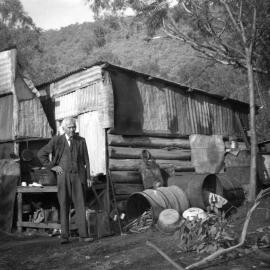 Man in bushland setting in front of a dwelling