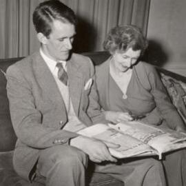 Malcolm Fraser looking at a book of newspaper cuttings with his mother, Una Fraser.