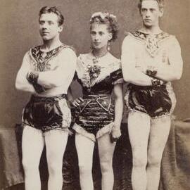 Two young men and a young woman in theatrical costumes.