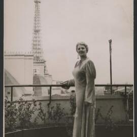 Louise Dyer in  floor-length gown with the Eiffel Tower visible in the background