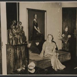 Louise Dyer in a long-sleeved, floor-length gown, seated in her rue Franklin apartment in front of her portrait