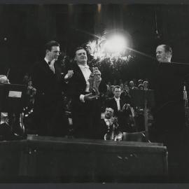 Jack Boyce (classical promotion manager at Decca), Thurston Dart and Secretary of State Dr. Y. Scholten standing on stage at the Grand Prix du Disque ceremony in 1958