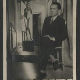 Italian painter Giovanni Colacicchi sitting with crossed legs in front of his 1924 oil on canvas La Malinconia