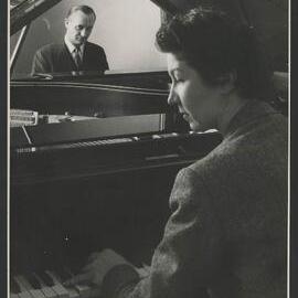 Unknown man sitting opposite Isabelle Nef at the piano, who is visible in side profile