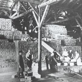 Men using machinery to assist in the stacking Red Cross parcels in a barn